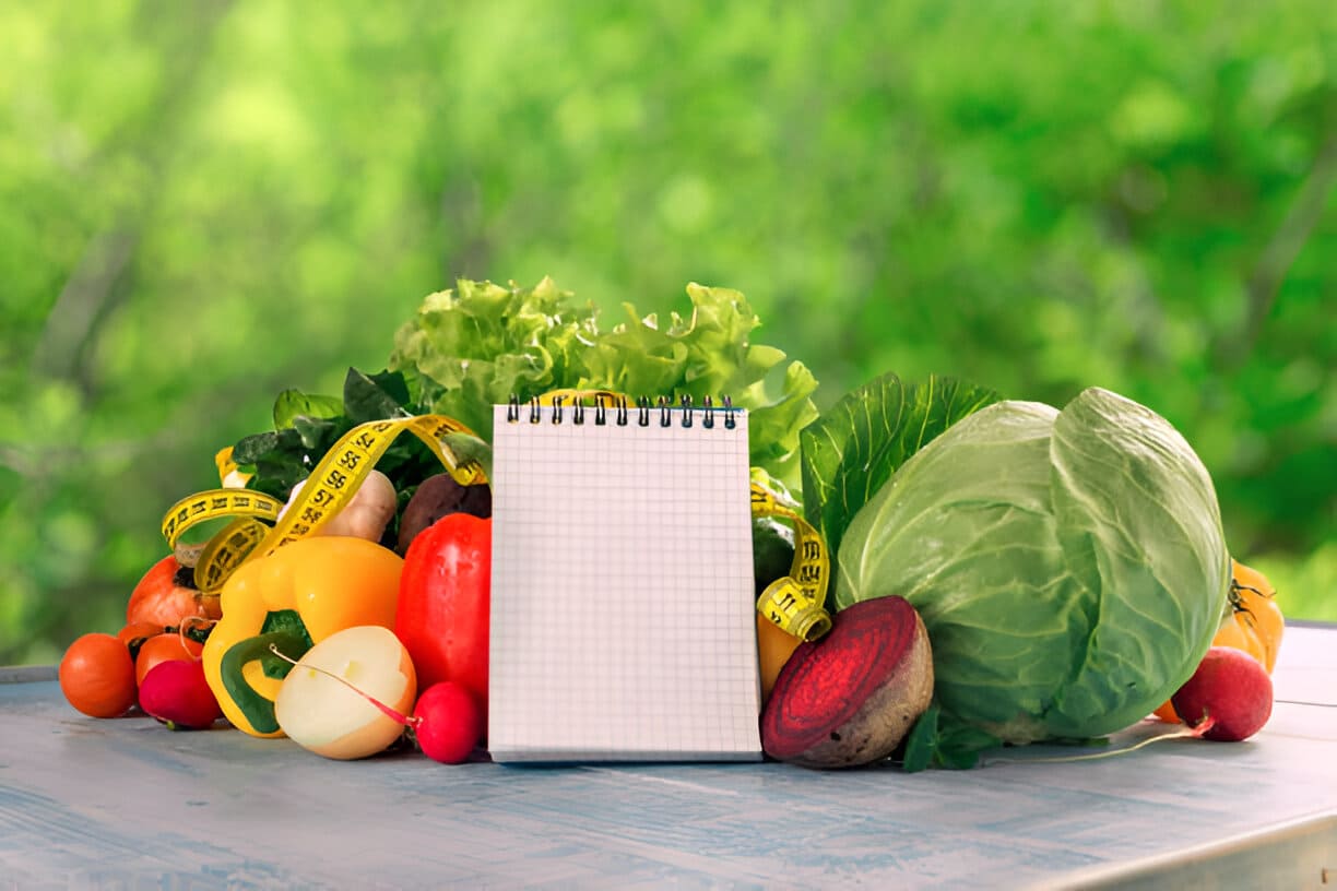 Ensemble de différents légumes frais avec une mesure de bande et bloc-notes vide