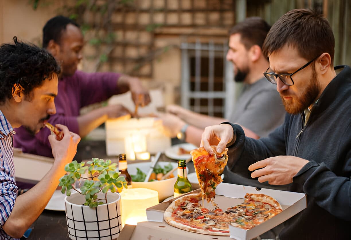 Groupe de sourire d’amis ayant la pizza